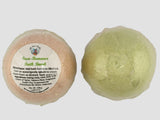 Two bath bombs, one pink and one green, on a light gray background.