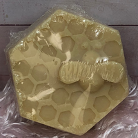Hexagonal soap with honeycomb design and bee figure on a textured surface