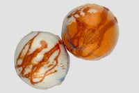 Two marbled beads, one orange and white, one white with brown and blue marbling, on a light gray background.